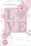 This anniversary card design presents a soft, romantic tableau, as if crafted to accompany an intimate evening at home in Charlton. The focal point is the word LOVE, softly raised from the card in pale, glittering letters that seem to glimmer like tiny lights along the Thames at dusk. The letter O is transformed into a shimmering silver heart, richly textured so it appears almost like hammered metal or a carefully polished charm on a bracelet. This heart gives the card a dimensional centrepiece, inviting fingers to rest there for a moment. The background is a symphony of pastel pinks and silvery greys, blending together in gentle gradients that suggest the colour of early morning skies seen above the rooftops near Charlton station. Encircling the central word is a wreath-like arrangement of delicate, illustrated blooms in blush, mauve, and gentle ivory, their petals lightly washed with watercolour softness. Fine, flowing lines form slender stems and tendrils that curl and intertwine, echoing the graceful movement of foliage in a hand-tied bouquet prepared for delivery across Charlton and nearby Blackheath. Tiny details-petals mid-fall, swirling curls, and subtle, barely-there butterflies-add a sense of quiet motion, as though the design were caught in a soft spring breeze. The phrases On Our Anniversary and I love you today and always are rendered in graceful, understated script, carefully placed so they feel woven into the floral design rather than printed over it. The overall effect is of a keepsake that whispers affection, ideal for marking years of shared memories with a card as tender and thoughtfully arranged as a bespoke arrangement from Charlton Florist.